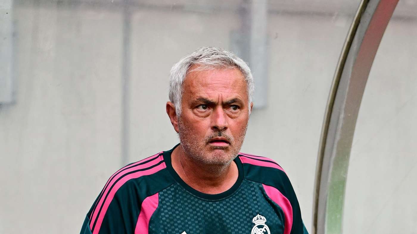Man with gray hair wearing a Real Madrid training jersey on the sideline, looking focused and concerned.