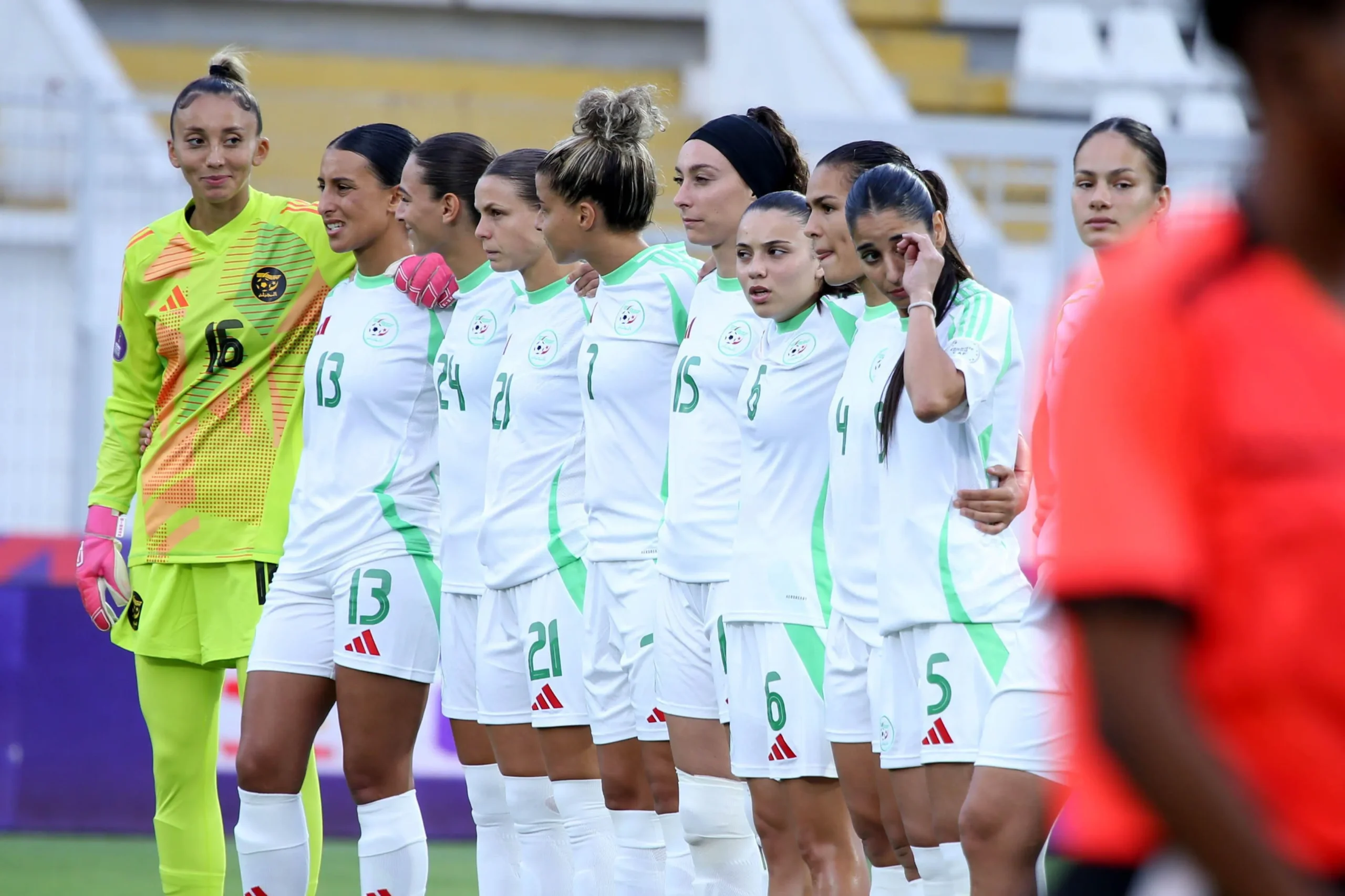 Women’s soccer team lined up together on the field, goalkeeper in neon yellow on the left.
