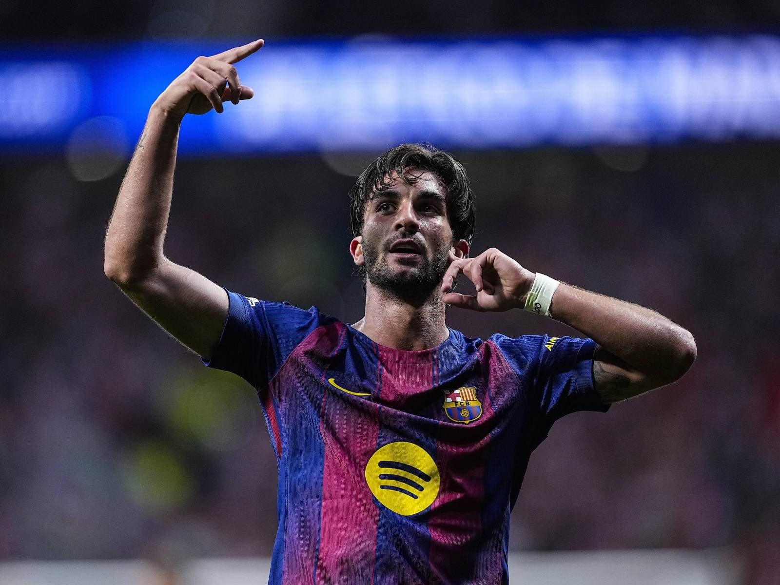 Soccer player in FC Barcelona kit raises arms in celebration on the pitch during a match Soccer player in FC Barcelona kit raises arms in celebration on the pitch during a match