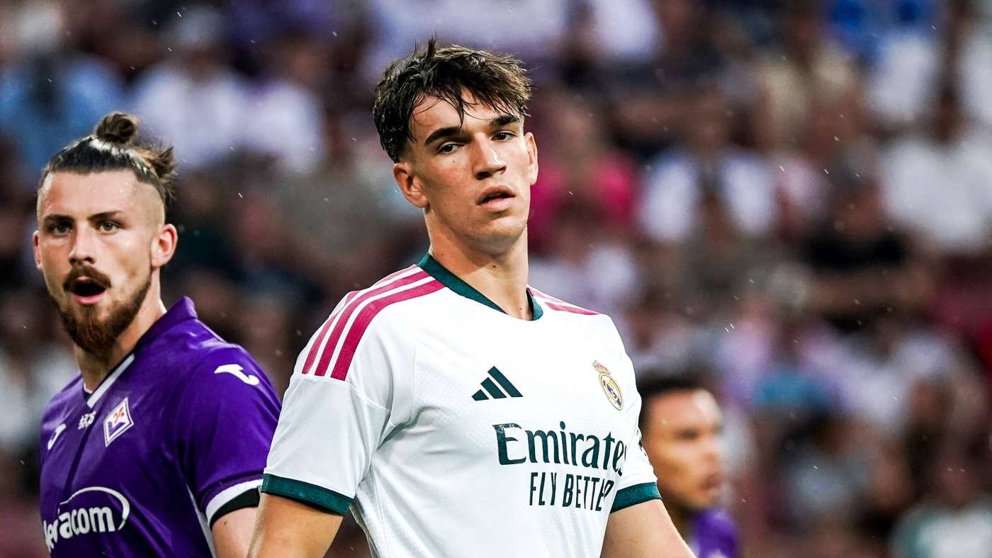 Soccer player in a Real Madrid white jersey stands on the field during a match, raindrops visible in the foreground. Soccer player in a Real Madrid white jersey stands on the field during a match, raindrops visible in the foreground.