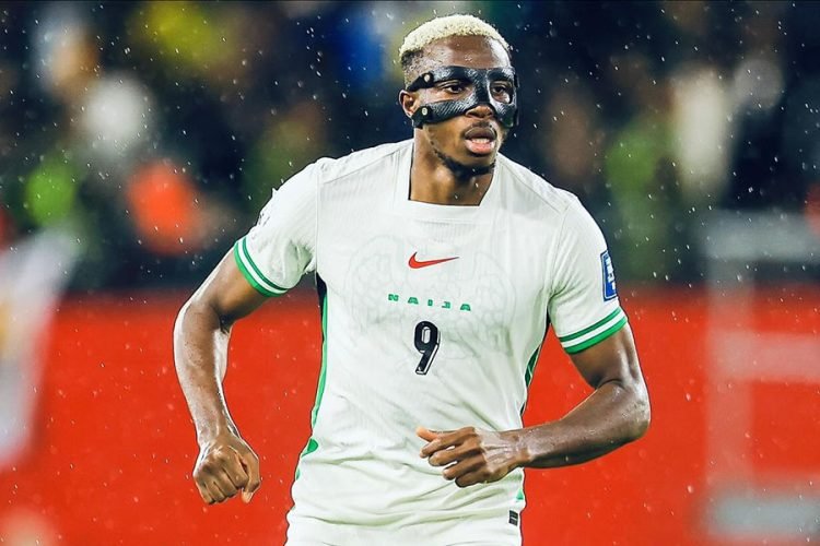 Footballer wearing a protective face mask and white jersey with number 9, sprinting on a rainy stadium field.
