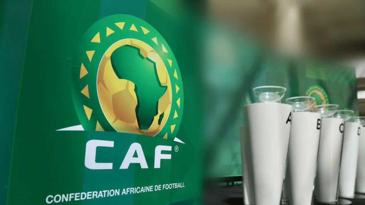 CAF logo on a green banner with a gold Africa map emblem and a row of white trophies beside it, representing the Confederation Africaine de Football.