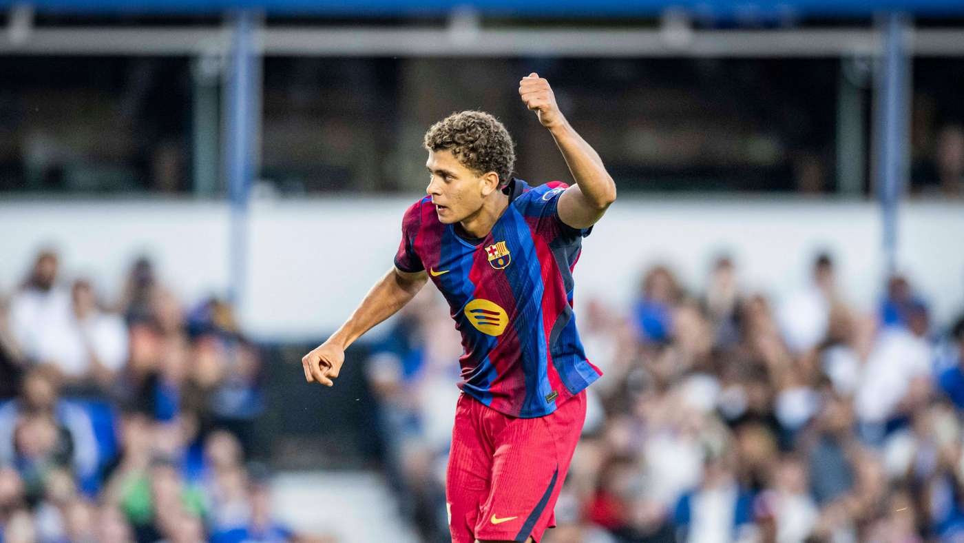 Soccer player in FC Barcelona colors celebrating a goal with his fist raised on the field of play.