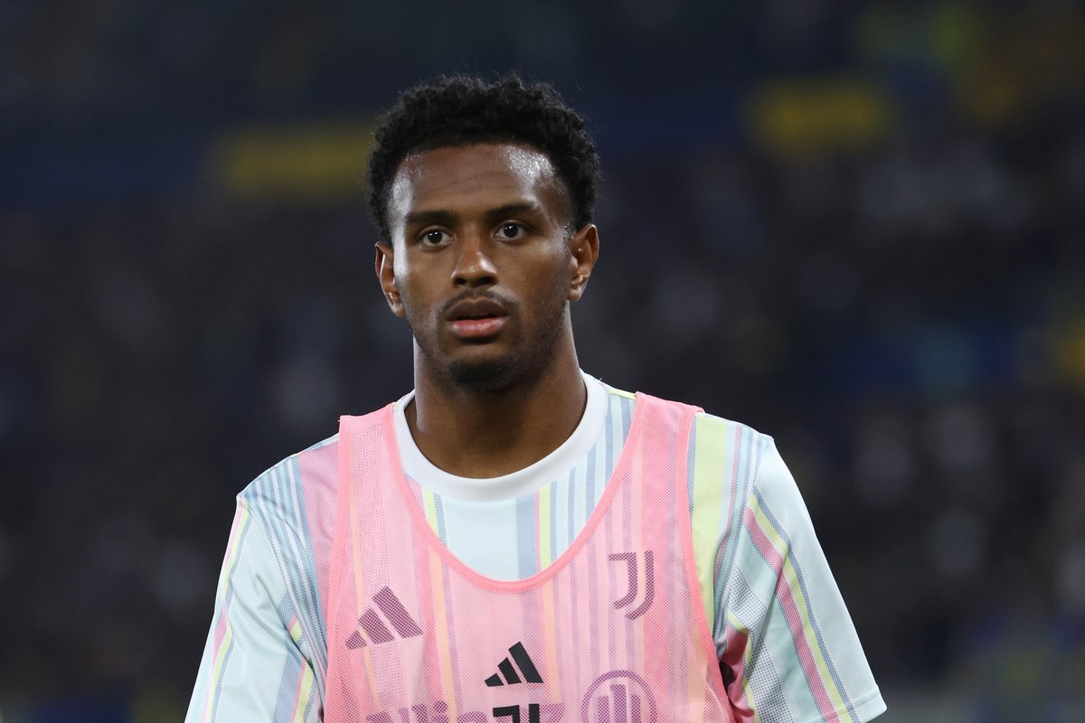 Soccer player wearing a pink Juventus training bib on the pitch, looking focused.