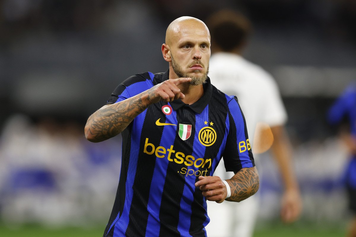 Bald soccer player in blue-and-black Inter Milan jersey points forward during a match.