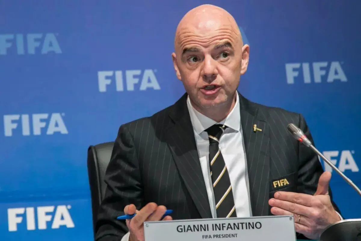 Gianni Infantino, FIFA President, speaking at a press conference with a blue FIFA backdrop and a nameplate in front of him Gianni Infantino, FIFA President, speaking at a press conference with a blue FIFA backdrop and a nameplate in front of him