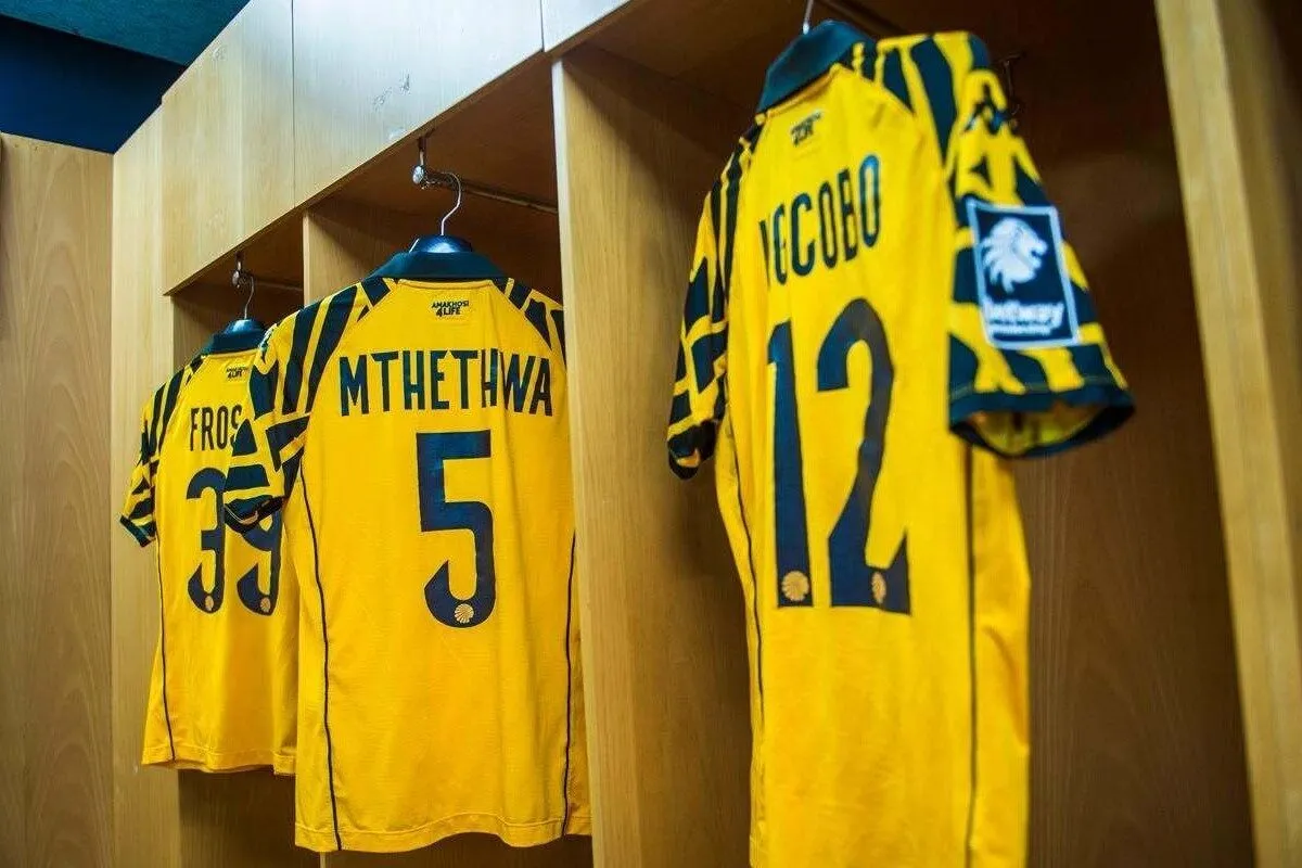 Three yellow sports jerseys hanging in wooden locker cubbies, showing numbers 5 and 12 as part of a team locker room display.