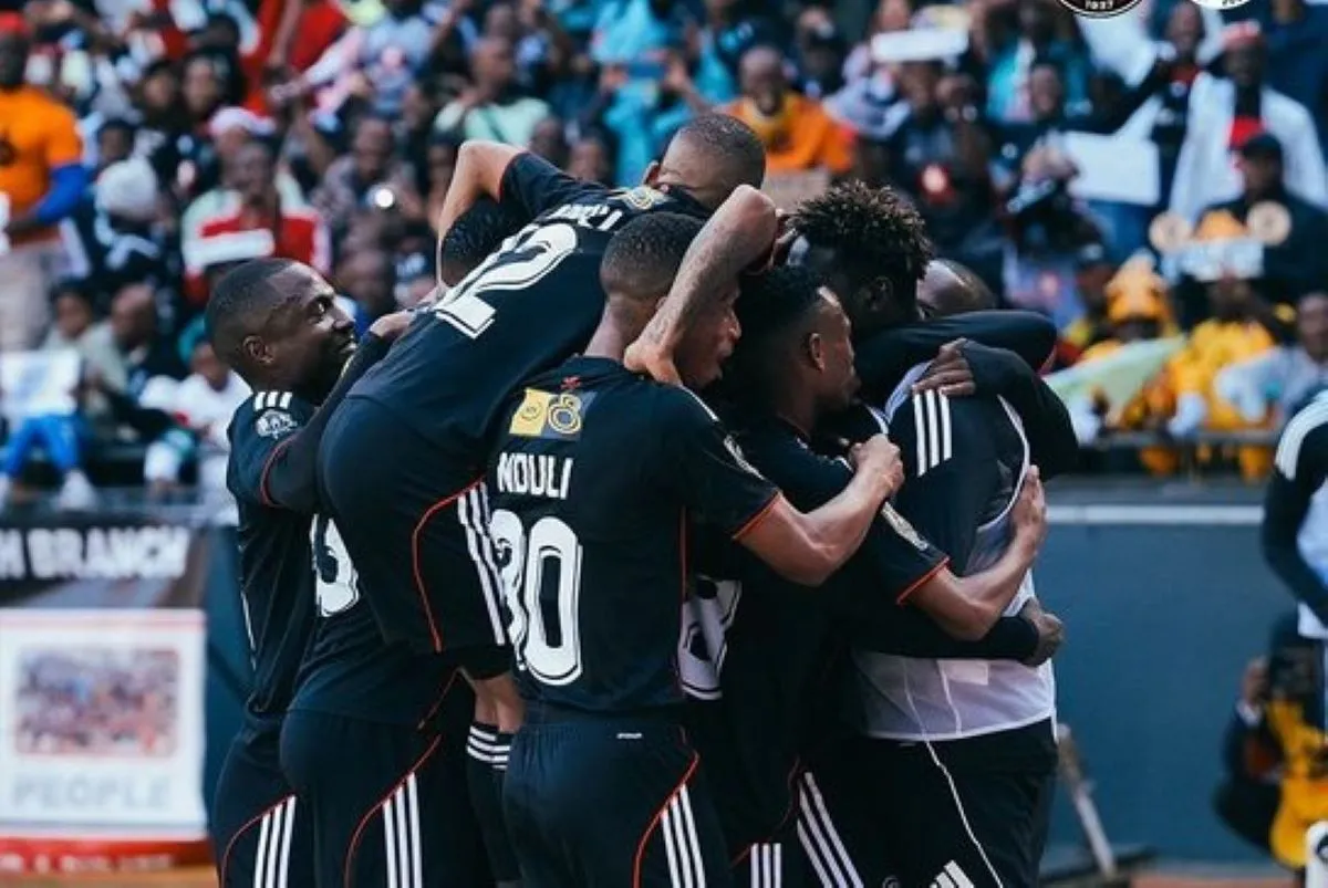 Soccer players in dark uniforms huddle together in celebration on the field.