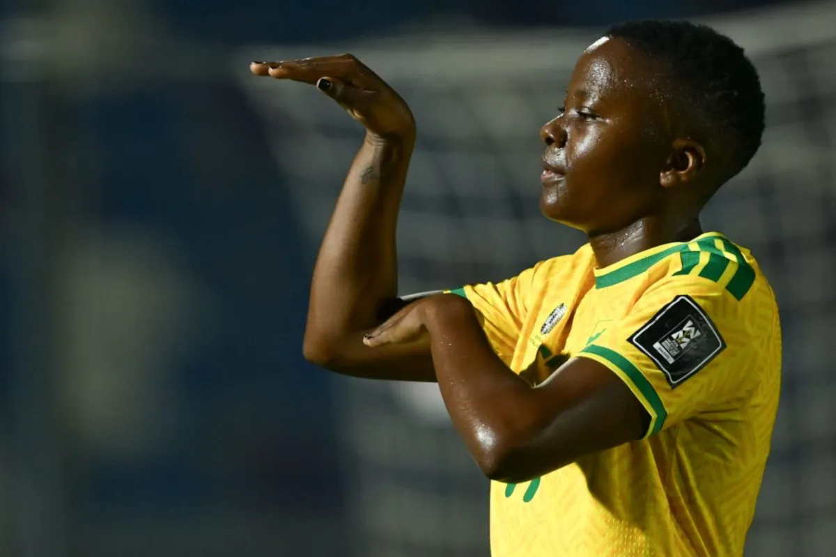 Soccer player in a yellow jersey with green trim saluting with his right hand during a game.