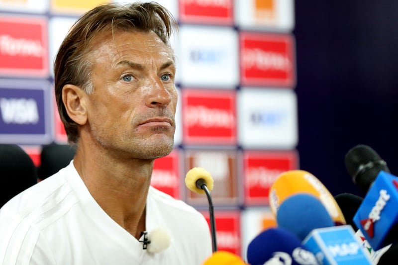 Man at a press conference speaking into a microphone with sponsor boards behind him.