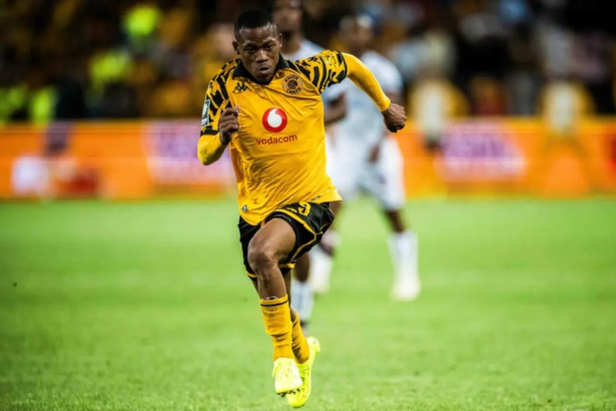 Soccer player in a yellow kit sprinting on a green pitch with a Vodacom logo on his chest.