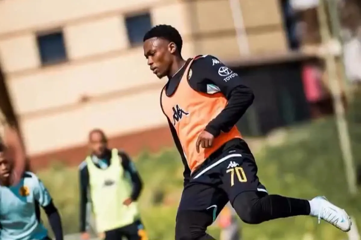 Soccer player in an orange training vest sprinting on a field during practice.